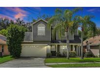 Two-story house with gray siding, beige garage door, and palm trees at 605 Brightview Dr, Lake Mary, FL 32746