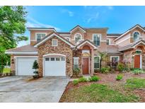 Two-story stucco home with stone accents, two-car garage, and landscaped yard at 7615 Bay Port Rd # 36, Orlando, FL 32819