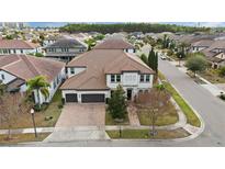 Two-story house with a three-car garage, brick paver driveway, and landscaping at 8558 Morehouse Dr, Orlando, FL 32836