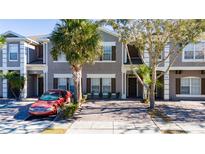 Two-story townhome with gray siding, paver driveway, and palm trees at 2394 Caravelle Cir, Kissimmee, FL 34746