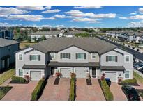 Aerial view of townhouses with gray siding, gray roofs, and brick pavers at 12067 White Wave Pt, Orlando, FL 32828