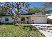 Brick ranch home with solar panels, carport, and landscaped lawn at 1708 Hope Dr, Ormond Beach, FL 32174