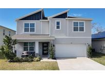 Two-story house with gray siding, dark gray roof accents, and a two-car garage at 236 Talisi Loop, St Cloud, FL 34771