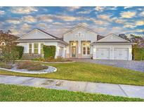 Two-story home with gray siding, three-car garage, and landscaped front yard at 2423 Hyatt Creek Ln, Port Orange, FL 32128