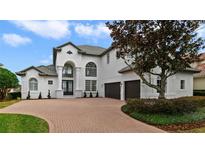 Two-story house with a white exterior, dark garage doors, and a brick driveway at 408 Chelsea Ave, Davenport, FL 33837