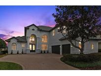 Elegant two-story home boasts a brick driveway and lush landscaping at 408 Chelsea Ave, Davenport, FL 33837