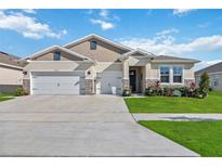 Two-story house with a three-car garage and landscaped yard at 6922 Audobon Osprey Cv, Harmony, FL 34773