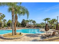 Large community pool with comfortable lounge chairs and palm trees at 8801 Worldquest Blvd, Orlando, FL 32821