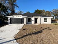 Newly constructed home with a modern design, featuring a gray stone facade and a black garage door at 102 Colomba Rd, Debary, FL 32713