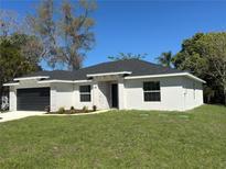 Charming single-story home featuring a stone accent wall, well-kept lawn, and a black two-car garage at 102 Colomba Rd, Debary, FL 32713