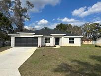 Charming one-story home featuring a dark gray two-car garage and well-maintained lawn at 102 Colomba Rd, Debary, FL 32713