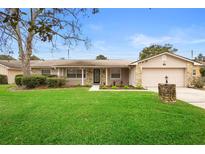 Tan house with stone accents, landscaped lawn, and a two-car garage at 1266 Juliana Pl, Orlando, FL 32807