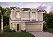 Two-story house with tan exterior, two-car garage, and landscaping at 1399 Sky Lakes Dr, Saint Cloud, FL 34769