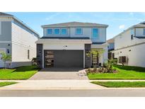 Two-story home with gray siding, dark gray garage door, and landscaped lawn at 16205 Saint Kitts Cir, Clermont, FL 34714