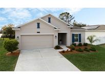 One-story house with beige exterior, neatly landscaped yard, and a two-car garage at 4530 Tahoe Cir, Clermont, FL 34714