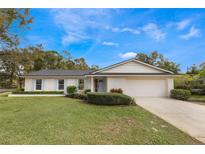 Ranch style home with white brick exterior, attached garage, and well-manicured lawn at 7884 Broken Arrow Trl, Winter Park, FL 32792