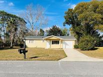 Cute yellow house with a white garage door and landscaped lawn at 8429 Sw 105Th Pl, Ocala, FL 34481