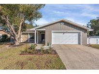 Cute ranch home with a white garage door and landscaped lawn at 1107 Lantana Dr, Eustis, FL 32726