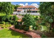 Serene backyard with gazebo, pond, and brick pathway. Lush landscaping surrounds the property at 11148 Lane Park Rd, Tavares, FL 32778