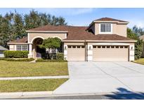 Two-story house with a three-car garage and well-manicured lawn at 13132 Coldwater Loop, Clermont, FL 34711