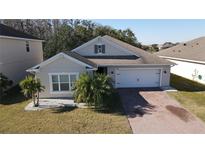 One-story home with gray exterior, brick driveway, and palm trees at 2408 Addison Creek Dr, Kissimmee, FL 34758