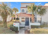 Two-story townhome with a tiled roof, gated entry, and landscaping at 4818 Marks Ter # 385 B2, Orlando, FL 32811