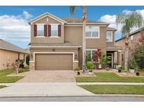 Two-story house with brown exterior, brick driveway, and landscaping at 648 Cortona Dr, Orlando, FL 32828