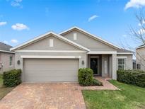 Tan one-story house with brick driveway and landscaping at 9653 Early Loop, Groveland, FL 34736