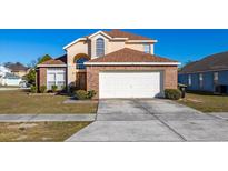 Two-story house with brick facade, attached garage, and well-manicured lawn at 108 Strait Dr, Davenport, FL 33897