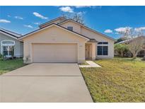 Tan two-story house with a double-car garage and a small front yard at 1448 Brook Hollow Dr, Orlando, FL 32824