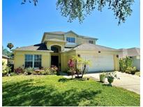 Two-story house with a landscaped yard and attached garage at 1708 Clubhouse Cv, Haines City, FL 33844