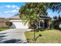 Tan house with white garage door, palm trees, and manicured lawn at 3427 Kayla Cir, Oviedo, FL 32765