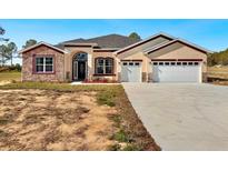 Two-story house with stone accents, three-car garage, and a large driveway at 41289 County Road, 452, Leesburg, FL 34788