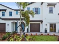 Two-story townhome with brown garage door, landscaping, and light blue shutters at 4418 Small Creek Rd, Kissimmee, FL 34744