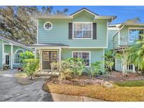 Two-story light green house with dark brown doors and landscaping at 5978 Braemar Pl # 108, Orlando, FL 32822