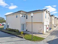 Tan two-story townhome with white door, attached garage, and landscaping at 7415 Lago De Oro # 2, Orlando, FL 32822