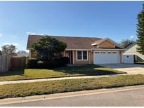 Tan house with a two-car garage and a fenced backyard at 1938 Gamboge Dr, Orlando, FL 32822
