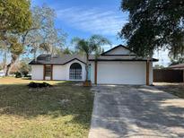 Newly renovated home with white exterior, fresh landscaping, and a two-car garage at 581 Calusa Ter, Deltona, FL 32738