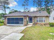 Brick ranch house with screened garage and landscaped yard at 120 Crooked Pine Rd, Port Orange, FL 32128