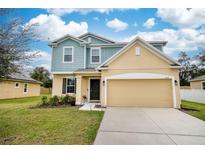 Two-story home showcasing a manicured lawn, two-car garage, and yellow and blue siding at 1319 Ralph Poe Dr, Apopka, FL 32703