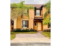 Tan two-story townhome with dark brown shutters and a paved driveway at 3428 Calabria Ave, Davenport, FL 33897