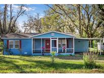 Charming light blue house with red door and screened porch at 4935 Sand Mountain Loop Rd, Auburndale, FL 33823