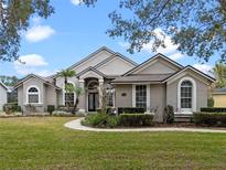 Tan two-story house with a lush lawn and landscaping at 9436 Wickham Way, Orlando, FL 32836