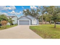 Gray house with a two-car garage and well-maintained lawn at 100 Kelly Cir, Sanford, FL 32773