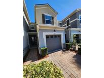 Two-story townhome with gray exterior, attached garage, and landscaped walkway at 3656 Brighton Park Cir, Orlando, FL 32812