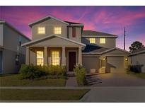 Two-story house with beige siding, a two-car garage, and landscaping at 3975 Great Smokey Way, Apopka, FL 32712