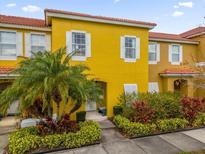 Bright yellow two-story townhome with landscaping and palm trees at 4765 Ormond Beach Way, Kissimmee, FL 34746