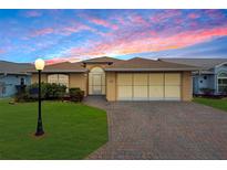 Charming single-story home boasting a brick driveway and manicured lawn under a vibrant sunset sky at 490 Sweetwater Way, Haines City, FL 33844