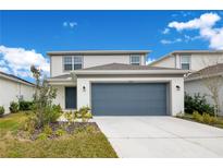 Two-story house with gray siding, two-car garage, and landscaping at 5302 Royal Point Ave, Kissimmee, FL 34746