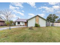 Light green house with brown metal roof, stone accents, and a landscaped yard at 628 Twin Oaks Cir, Daytona Beach, FL 32117